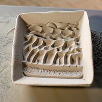 A sand sculpture with a wave design in it that evokes the ocean