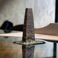 Image of a stone obelisk, perhaps 20 cm tall sitting in water