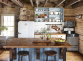 The kitchen is a medium sized rustic, vintage, farmhouse style with wood counters and dark tones.